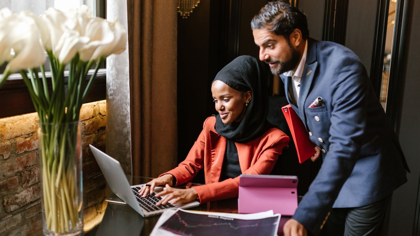 Business professionals working together on a laptop indoors, showcasing collaboration and modern technology.