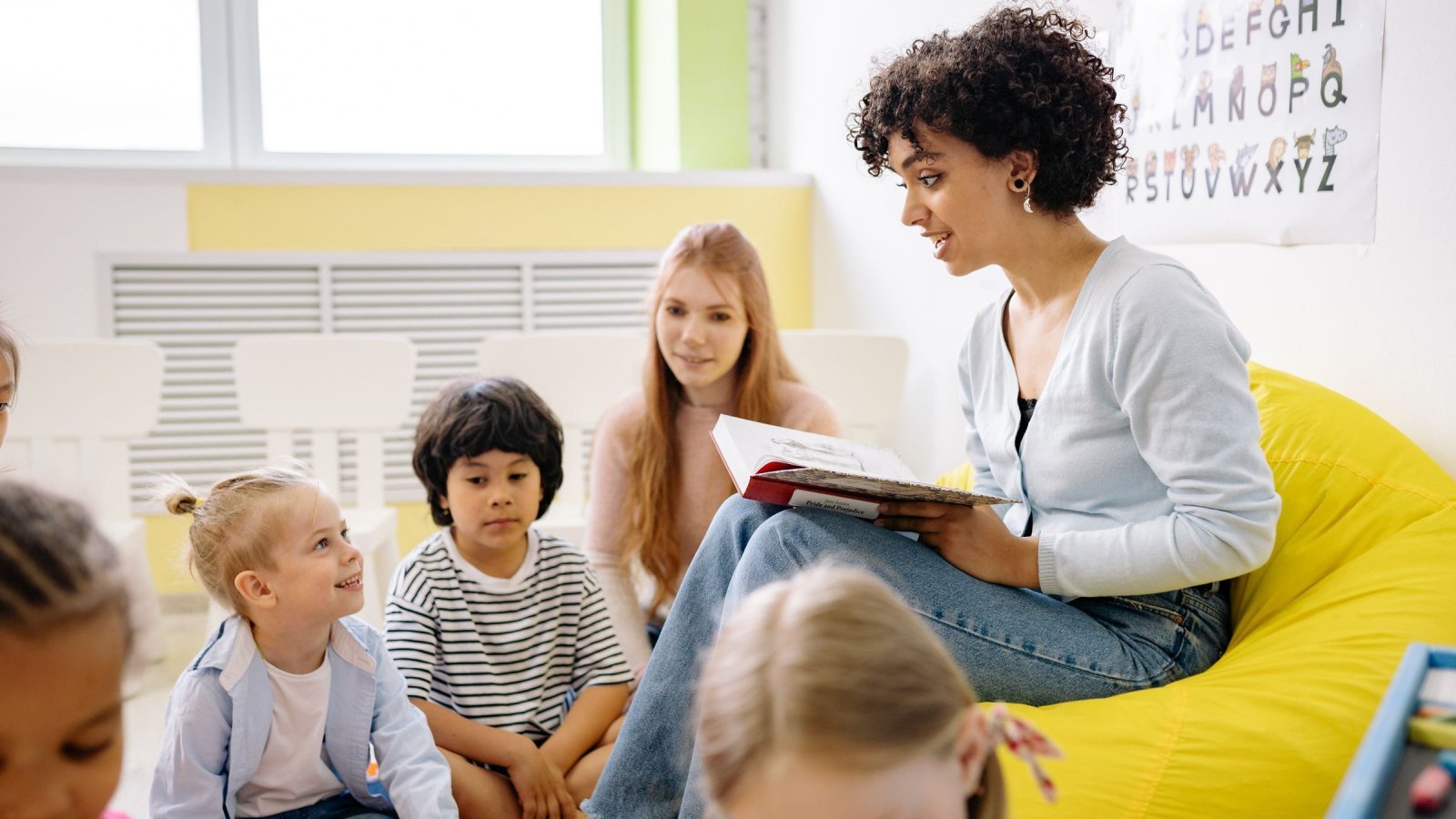 Teacher reading to preschool kids in a colorful classroom setting.