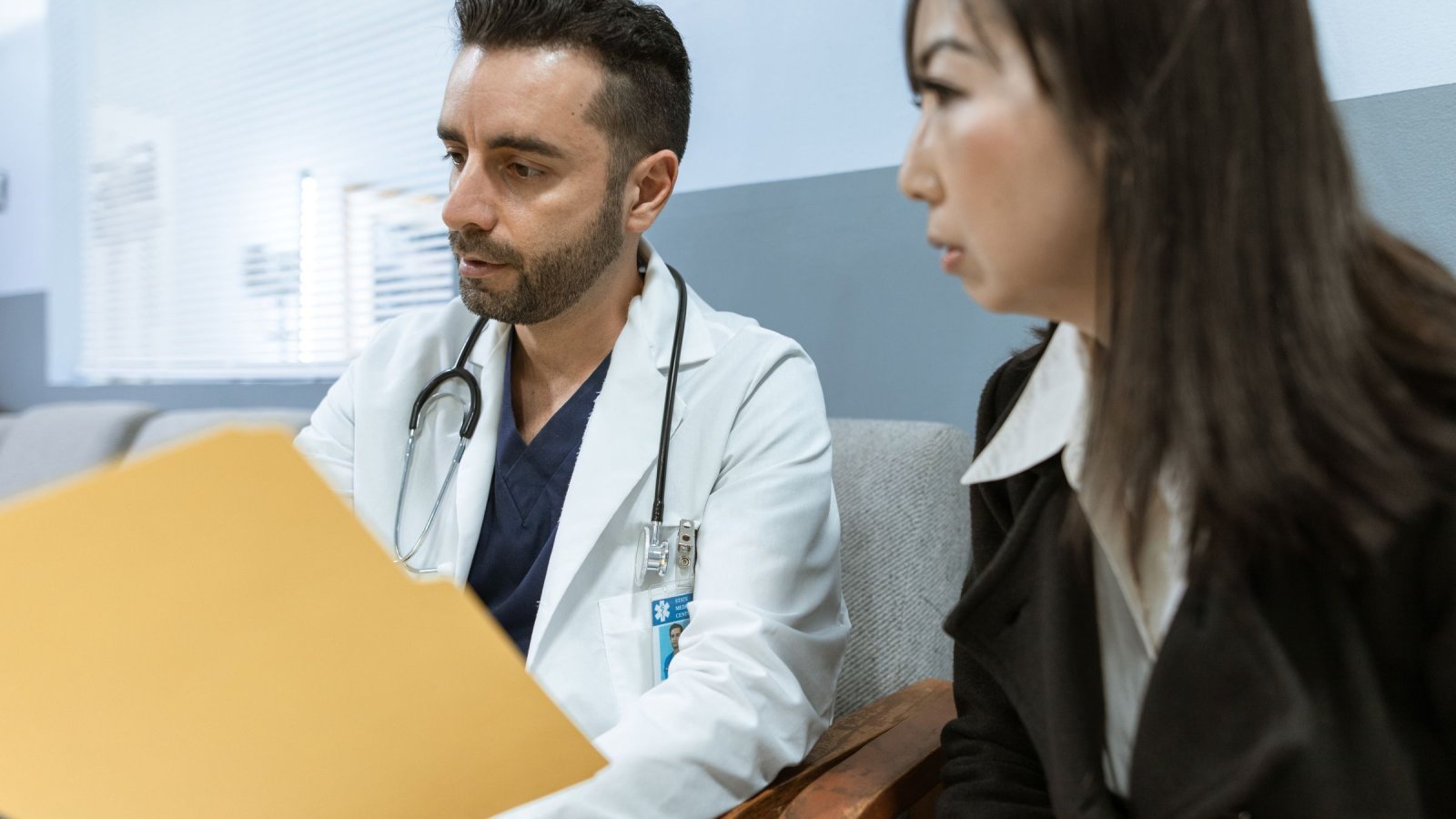 Doctor discusses health records with a patient in a clinical setting.