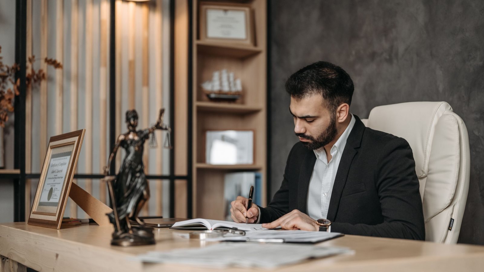 A focused lawyer in an office setting writing and reviewing legal documents, symbolizing expertise and professionalism.